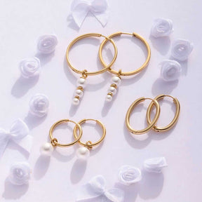 Creolen LUZIE gold mit Perlen, umgeben von weißen Rosen auf weißem Untergrund