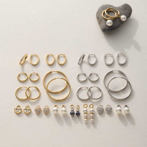 Umfangreiche Schmuckkollektion mit goldenen und silbernen Ringen, Ohrringen und Perlenanhängern auf weißem Untergrund