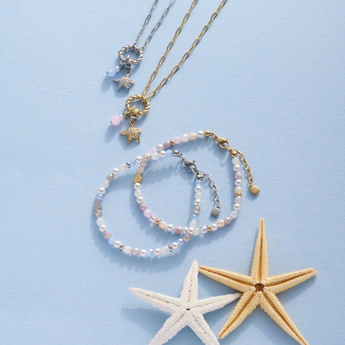 Armband FRANZI gold mit Perlen, Halsketten und Seesternen auf blauem Hintergrund