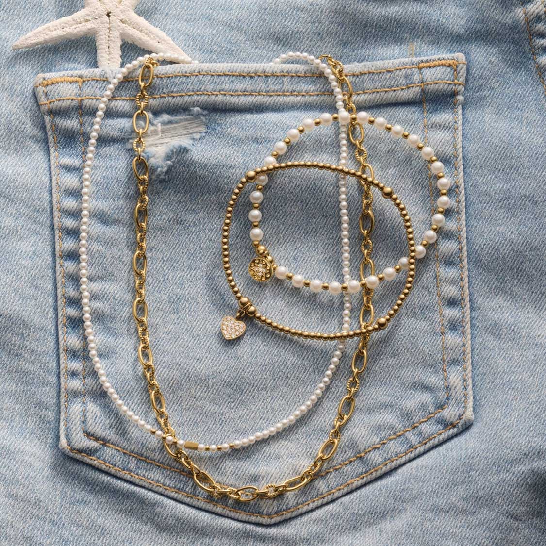 Halskette SOLVANI gold auf Jeanstasche mit Perlendetails