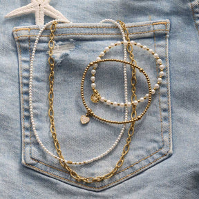Halskette SOLVANI gold auf Jeanstasche mit Perlendetails