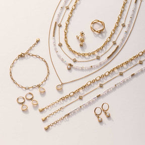 Goldene Halsketten, Armbänder und Ohrringe mit Perlen auf hellem Hintergrund arrangiert