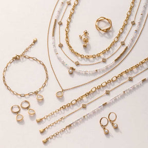 Goldene Ohrringe, Ringe, Ketten und Armbänder aus der Serie INDRA auf hellem Hintergrund