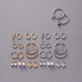 Schmuckkollektion mit goldenen und silbernen Ringen, Ohrringen und Anhängern auf grauem Hintergrund