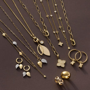 Schmuckkollektion mit Halsketten, Ringen und Armbändern in Gold- und Silbertönen mit Zirkonia auf grauem Hintergrund
