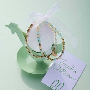Armband EVELYN gold You & Me CIAO auf grünem Dekoobjekt mit Geschenkband und Grußkarte
