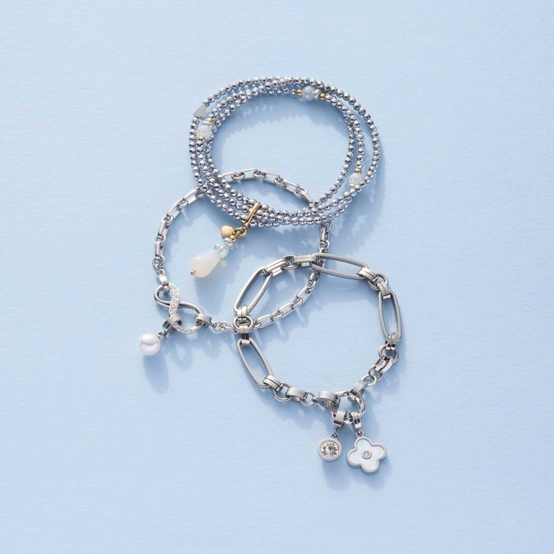 Armband NOURA Clip & Mix in Silber und Gold mit Perlen und Charms auf hellem Untergrund