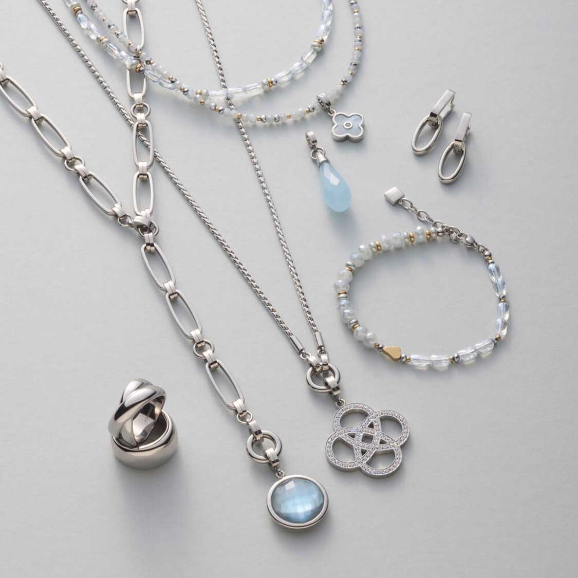 Silberne Schmuckkollektion mit Halskette, Armband, Ring und Ohrstecker auf grauem Hintergrund