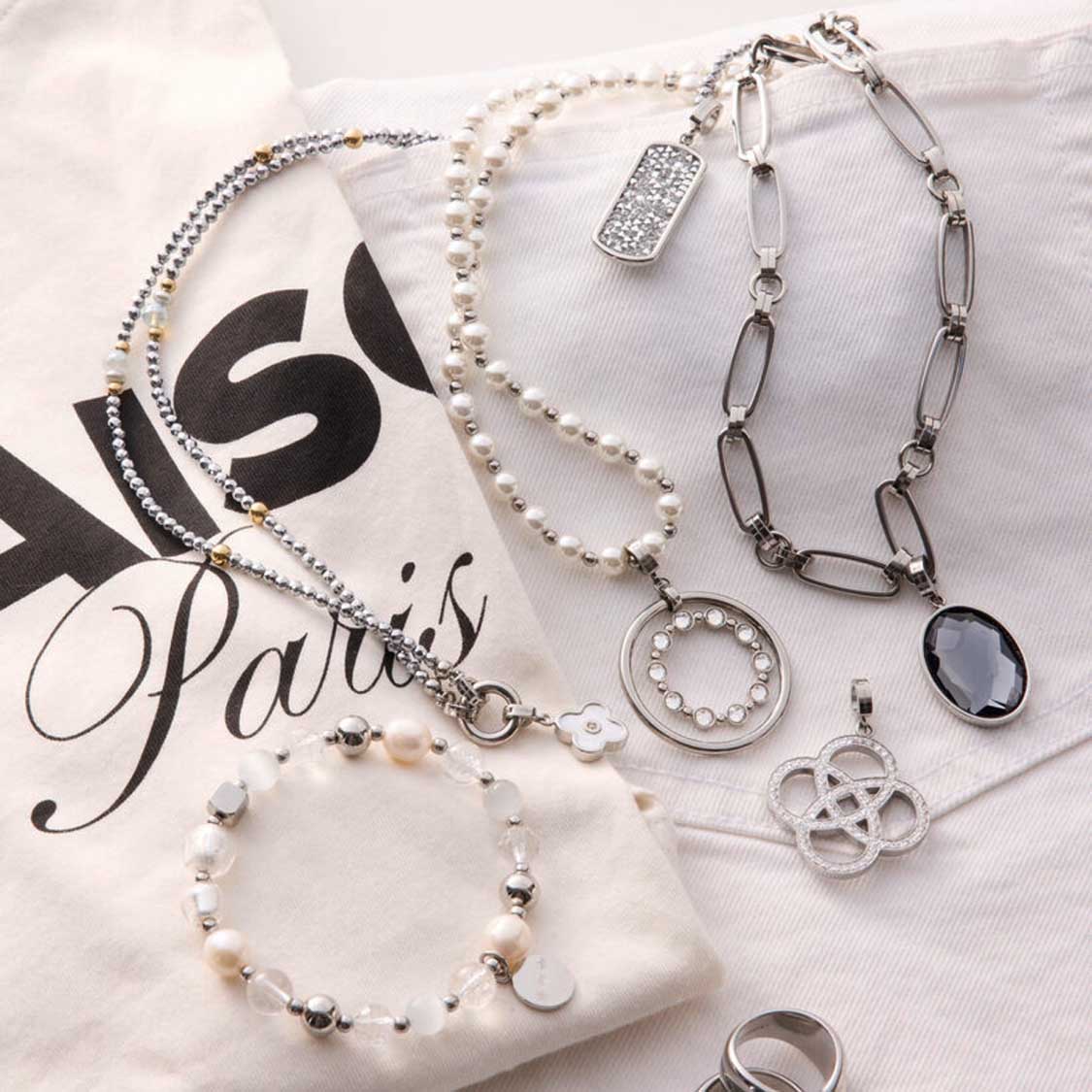 Mehrere Anhänger EDITH Clip & Mix auf Verpackung arrangiert, Perlenketten und Metallcharms in Silber