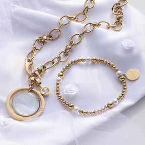 Anhänger MAGDA gold mit Kette und Perlenarmband auf weißem Stoff