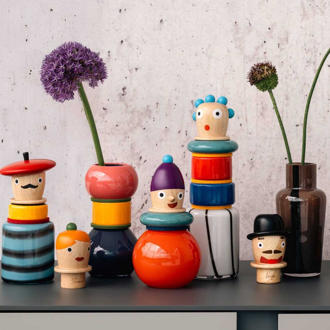 Dekorative Holzfiguren und bunte Glasvasen in Regal-Stillleben arrangiert