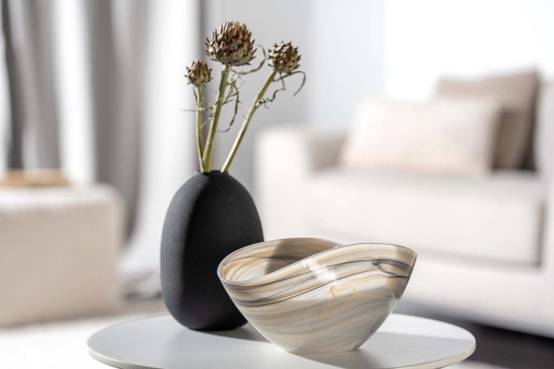 Schale ALABASTRO mit schwarzer Vase und Trockenblumen auf weißem Tisch im Wohnzimmer