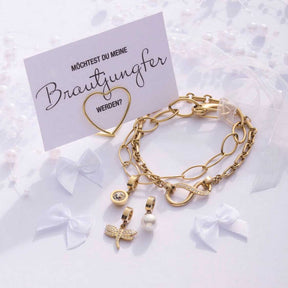 Goldene Armkette mit Charms und Anhängern auf Geschenkkarte mit Brautjungfer-Motiv