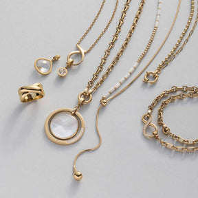 Goldene Schmuckkette mit Edelstahlring und verschiedenen Kettenanhängern auf Grau