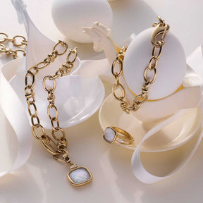 Ring VIRGINIA 21 gold mit Kette und Schmuckdisplays auf weißem Hintergrund