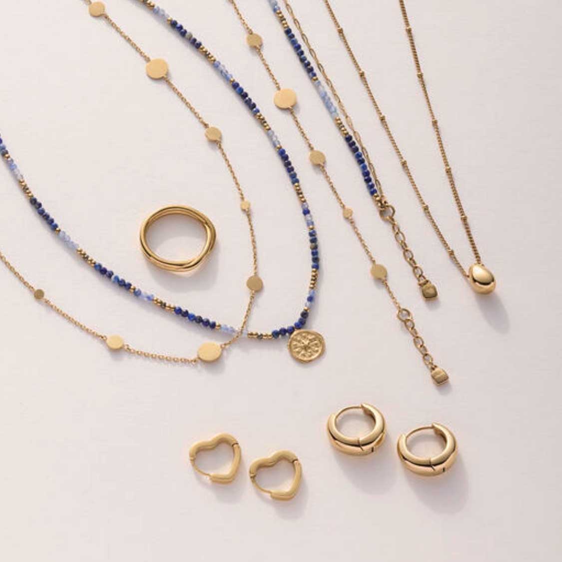 Creole LUVELLA gold CIAO mit Halsketten und Ringen auf heller Oberfläche