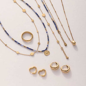 Creole LUVELLA gold CIAO mit Halsketten und Ringen auf heller Oberfläche