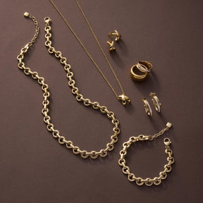 Halskette SOPHIE, Armband und Ringe aus Gold auf braunem Hintergrund