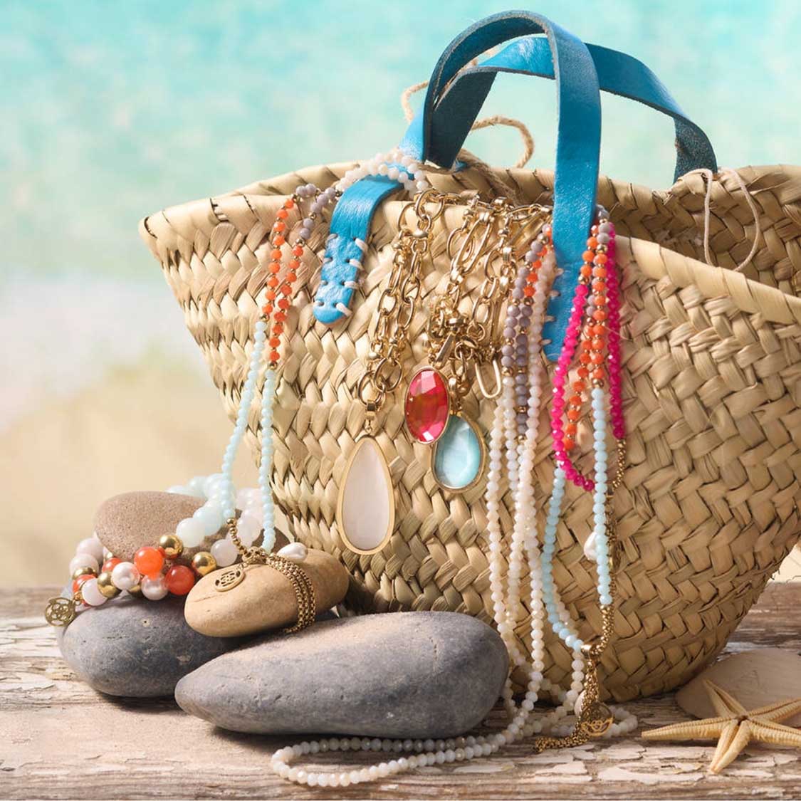 Halskette SOLERA mit Glasperlen neben Strohtasche am Strand