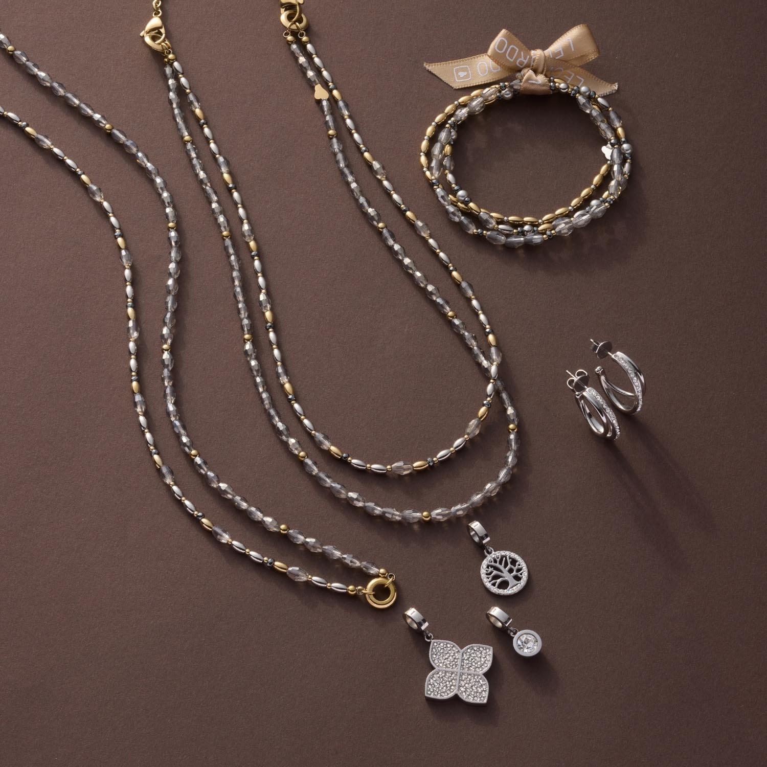 Halskette AGNETA mit Glasperlen, Anhängern und Armband auf braunem Hintergrund