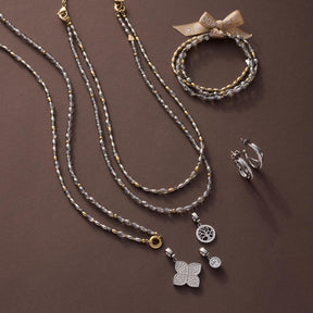 Halskette AGNETA mit Glasperlen, Anhängern und Armband auf braunem Hintergrund