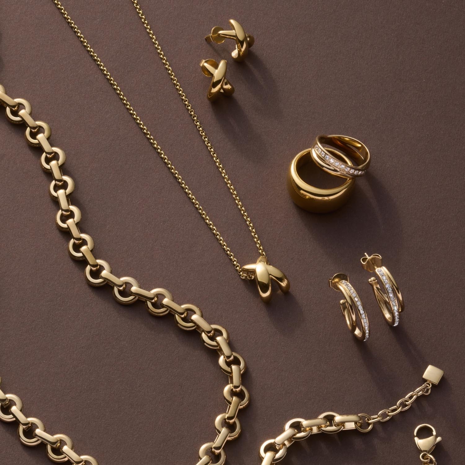 Goldschmuck Kollektion mit Ring DARIA 20, Ketten und Ohrringen auf grauem Hintergrund