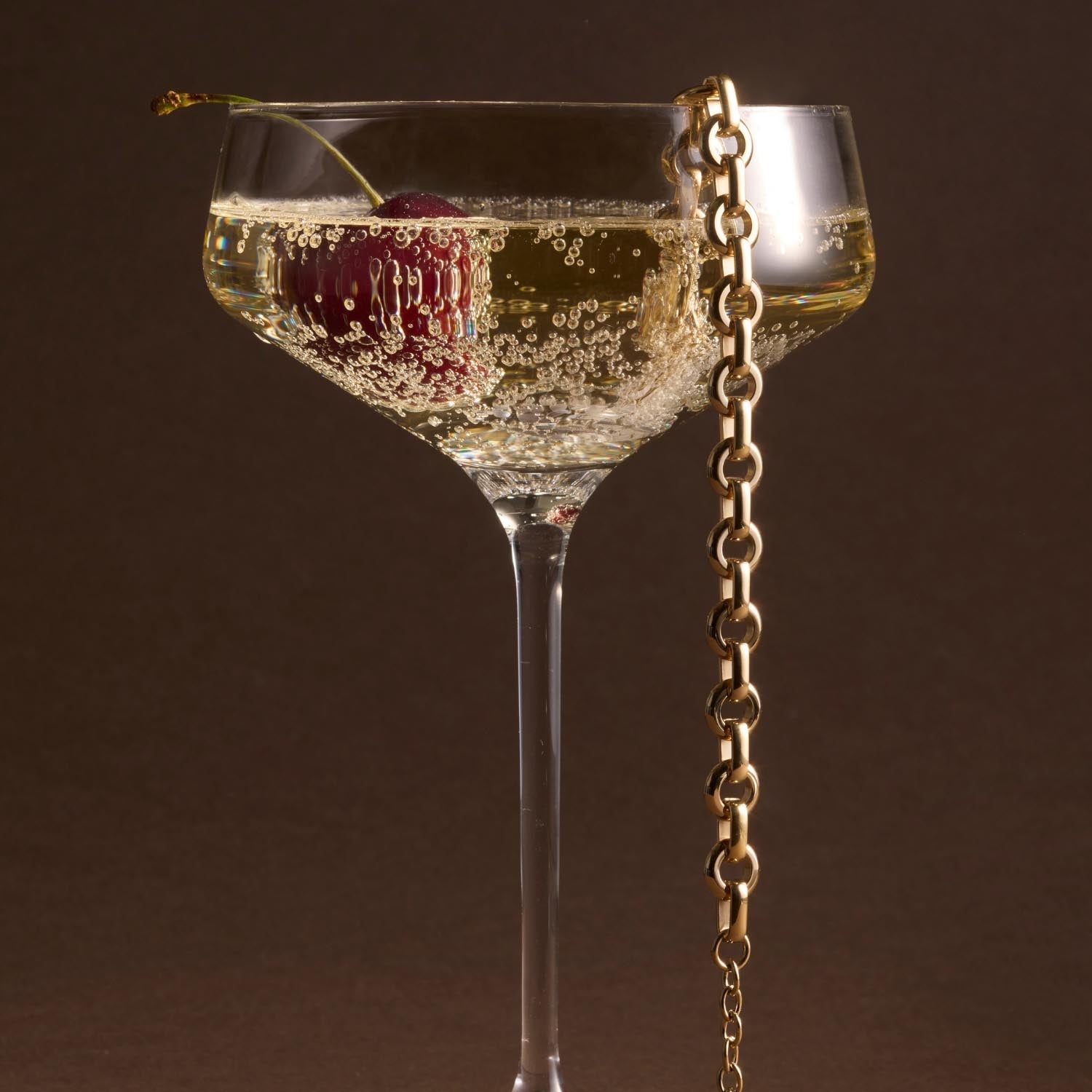 Armband NALA in Gold neben Champagnerglas mit Perlen