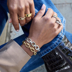Zwei Personen mit Goldringen und goldenem Kettenarmband, blaue Jeansjacke, schwarze Tasche