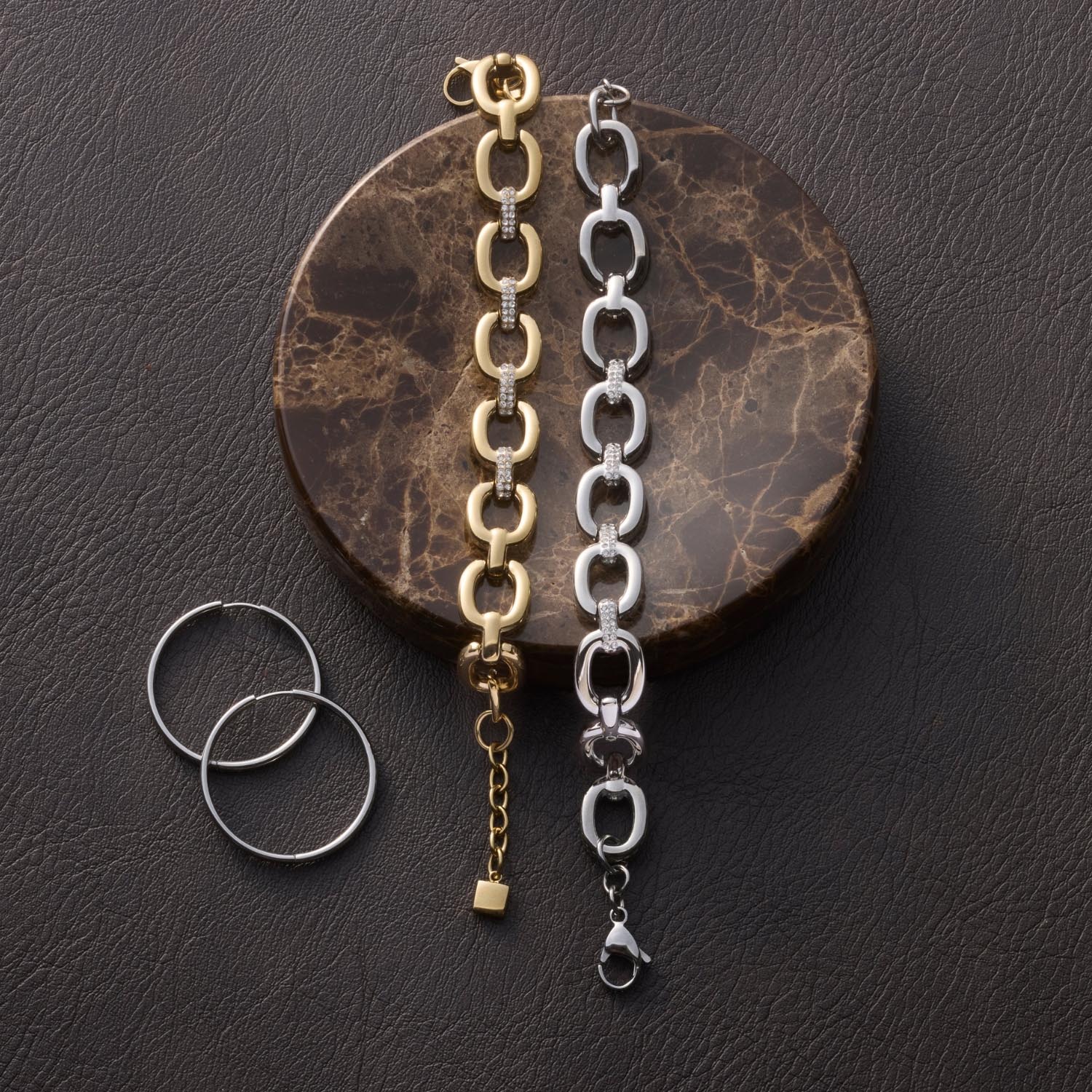 Armband BELLE gold und Silber mit Gliederkette auf marmoriertem Untergrund, daneben zwei silberne Ringe