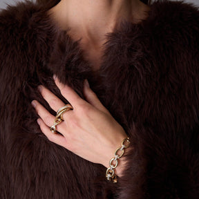 Frau trägt goldenen Ring BELLE 19 und Armband an der Hand, dunkelbraunes Fell im Hintergrund