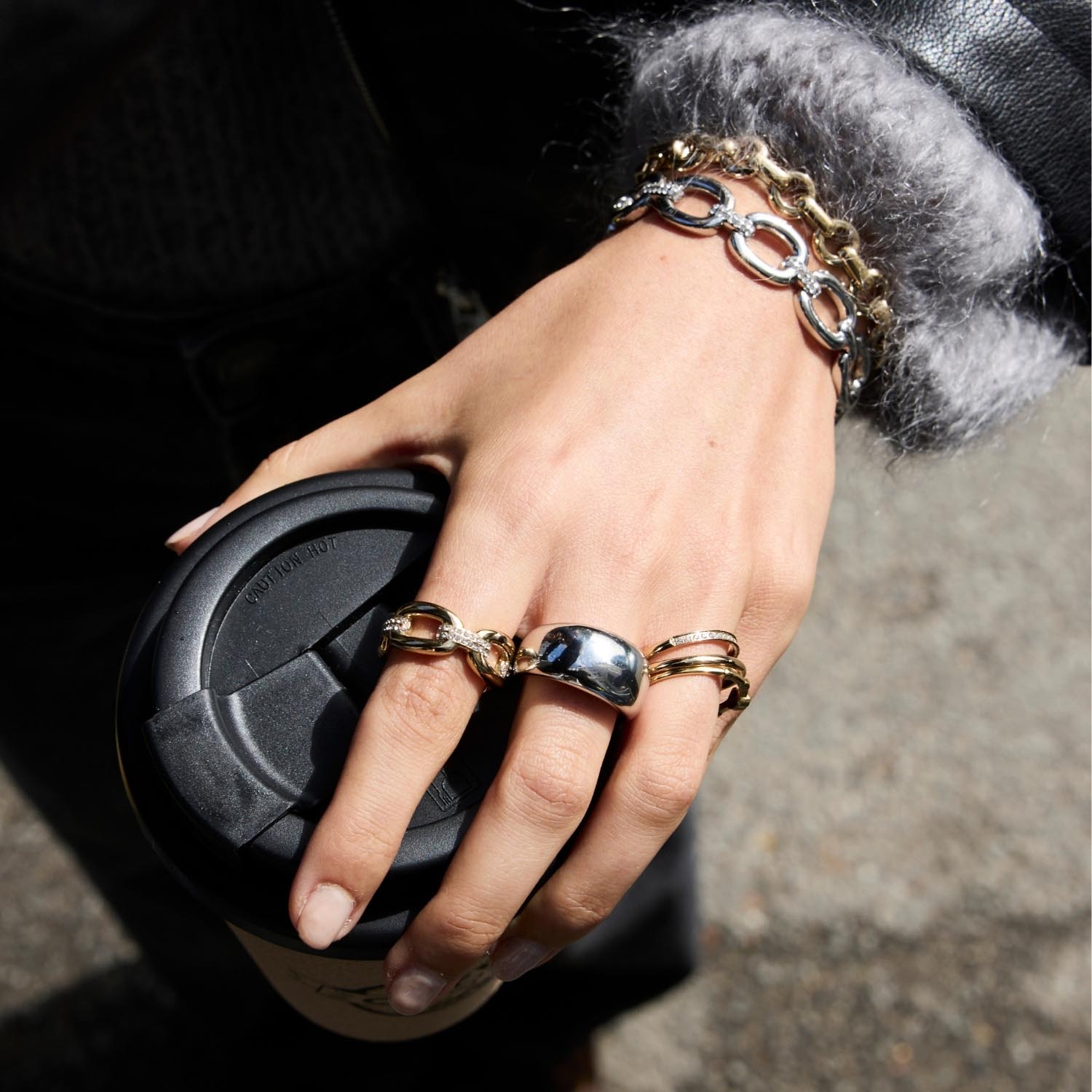 Hand mit Ring BELLE 20 gold, Armband und schwarzer Tasche