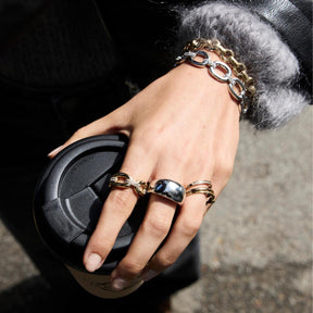 Hand mit Ring BELLE 21 gold, Armband und schwarzer Handtasche