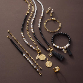 Armband EVE mit schwarzen Perlen, Kettengliedern und goldfarbenen Akzenten auf grauem Hintergrund