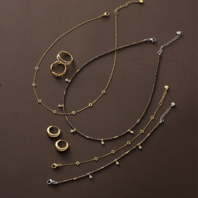 Halskette ANNA, Ringe und Armbänder in Gold und Silber auf braunem Untergrund arrangiert