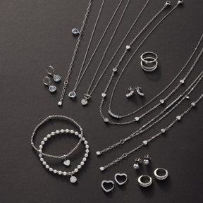 Silberne Halsketten, Armbänder, Ringe und Ohrringe auf schwarzem Hintergrund arrangiert
