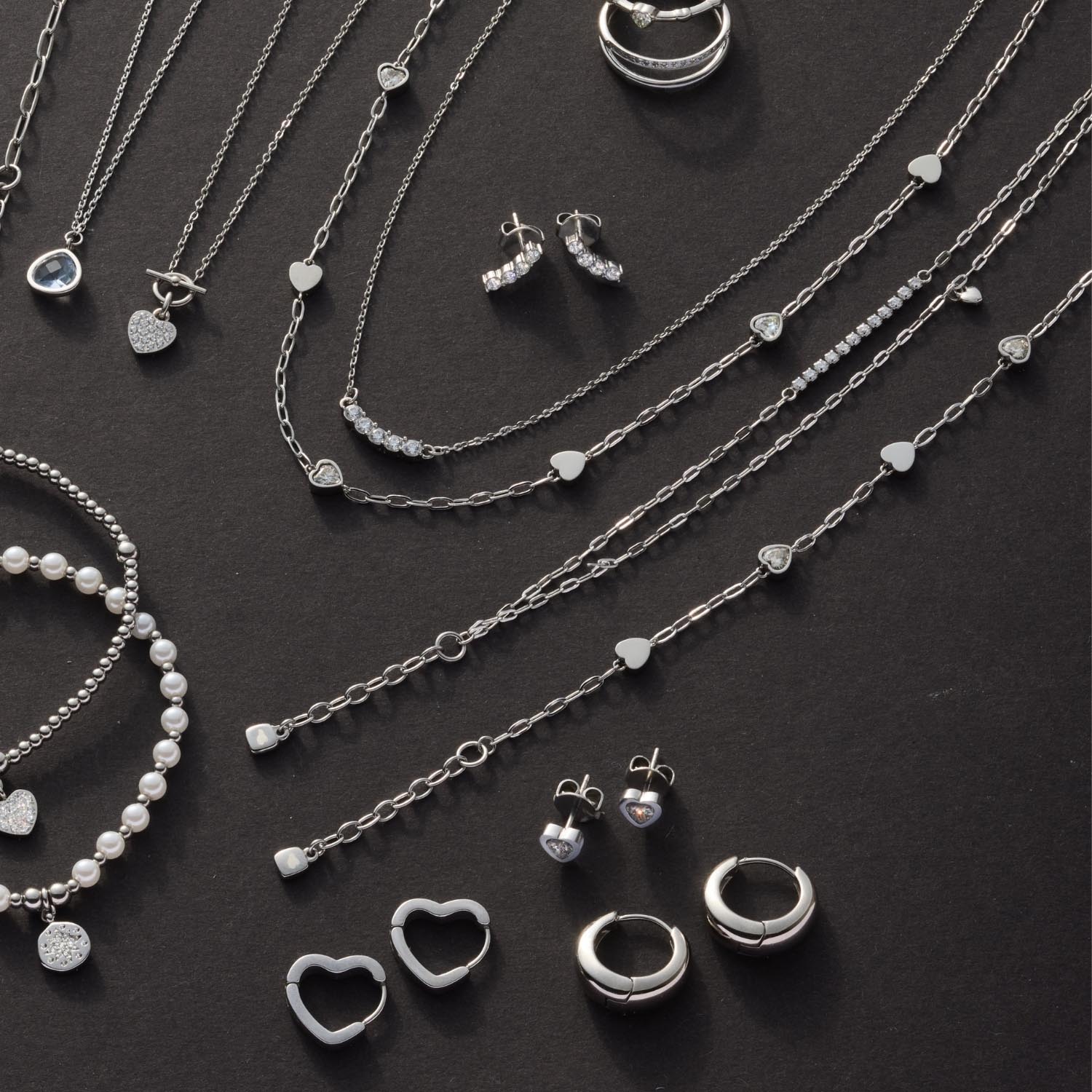 Silberner Schmuck auf dunklem Hintergrund: Halsketten, Ohrringe, Armband TINI CIAO und Ringe