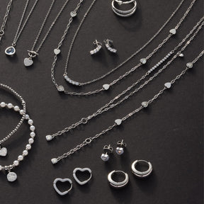 Silberner Schmuck auf dunklem Hintergrund: Halsketten, Ohrringe, Armband TINI CIAO und Ringe