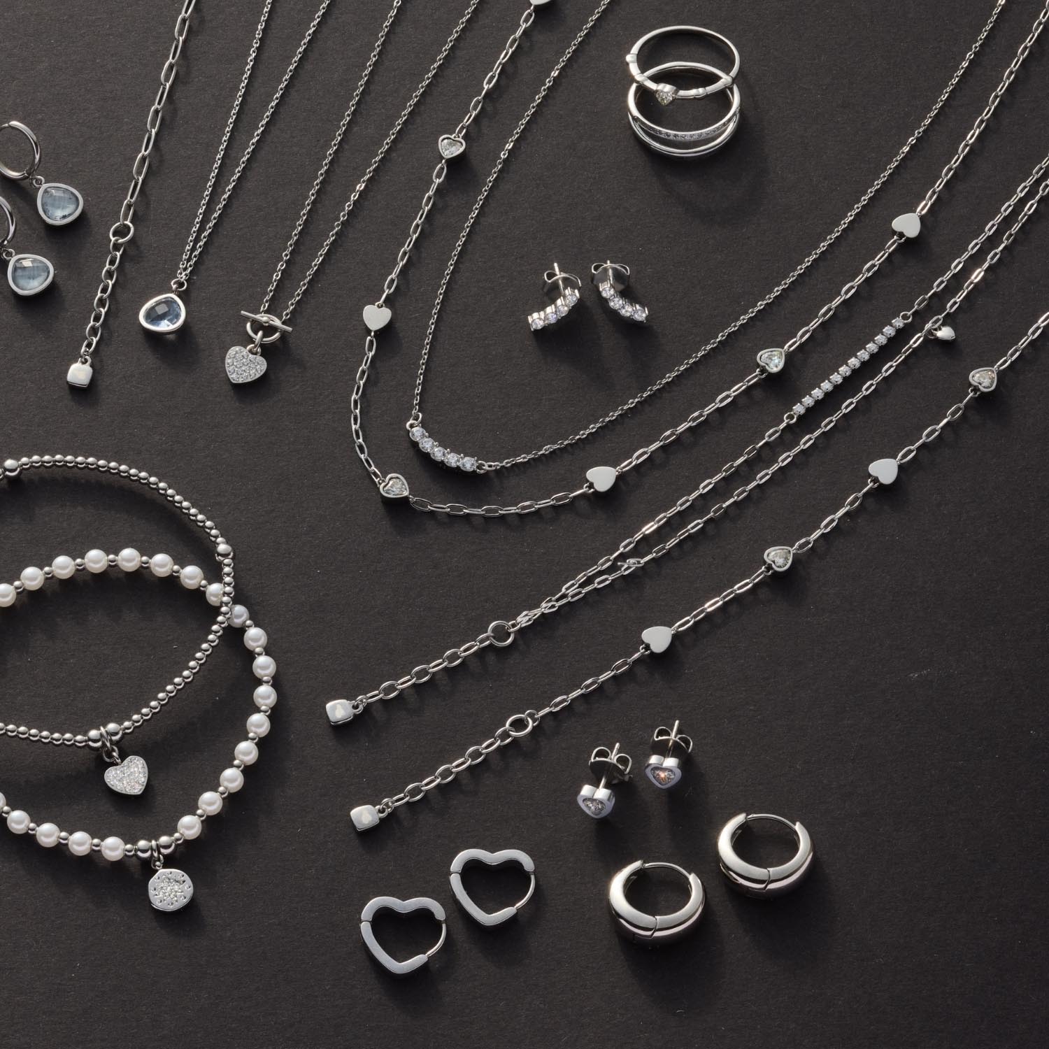 Schmuckkollektion mit Halsketten, Ringen, Ohrringen und Armband auf dunklem Hintergrund