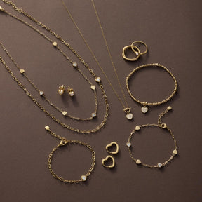 Goldener Schmuck auf braunem Hintergrund: Halsketten, Armbänder, Ringe und Ohrringe
