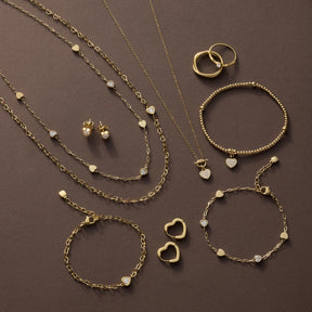 Goldene Schmuckkollektion mit Armbändern, Ketten, Ringen und Ohrringen auf braunem Hintergrund