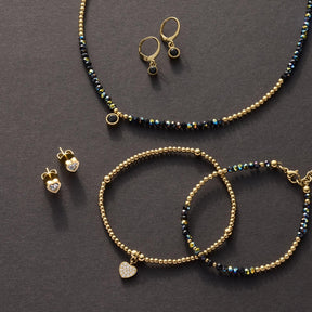 Ohrstecker CHRISTIE gold CIAO mit Zirkonia, Armband und Halskette auf grauem Untergrund