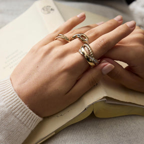 Hand mit mehreren Ringen VERA 17 gold auf offener Buchseite