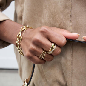 Hand mit Ring VERA 18 gold, Armband und beigefarbenem Pullover