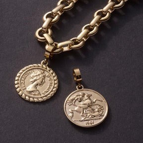 Goldene Kette mit zwei Münz-Anhängern auf grauem Untergrund