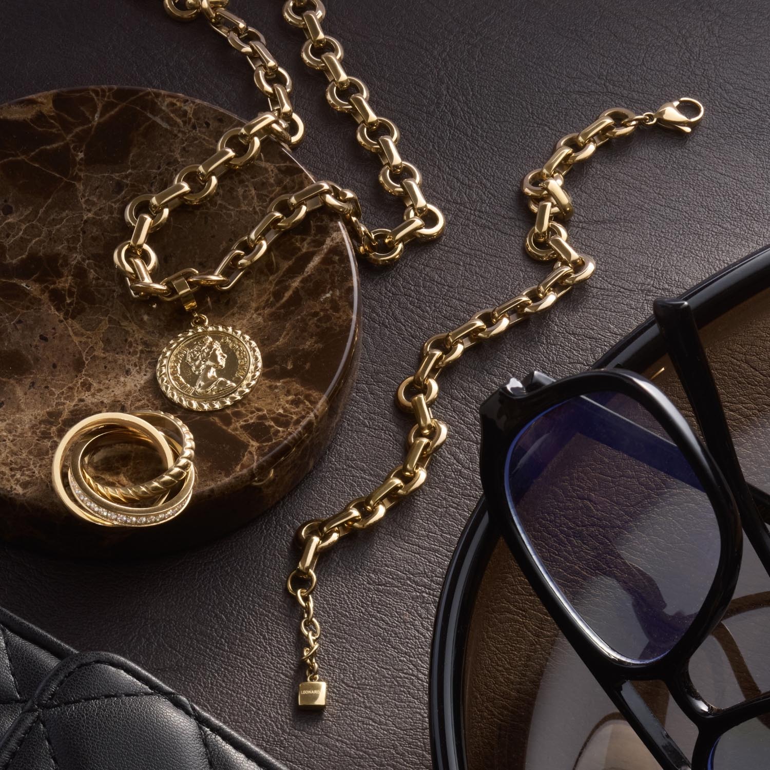 Anhänger LISBETH Clip & Mix mit Kette und weiteren Schmuckaccessoires auf Leder neben schwarzer Brille
