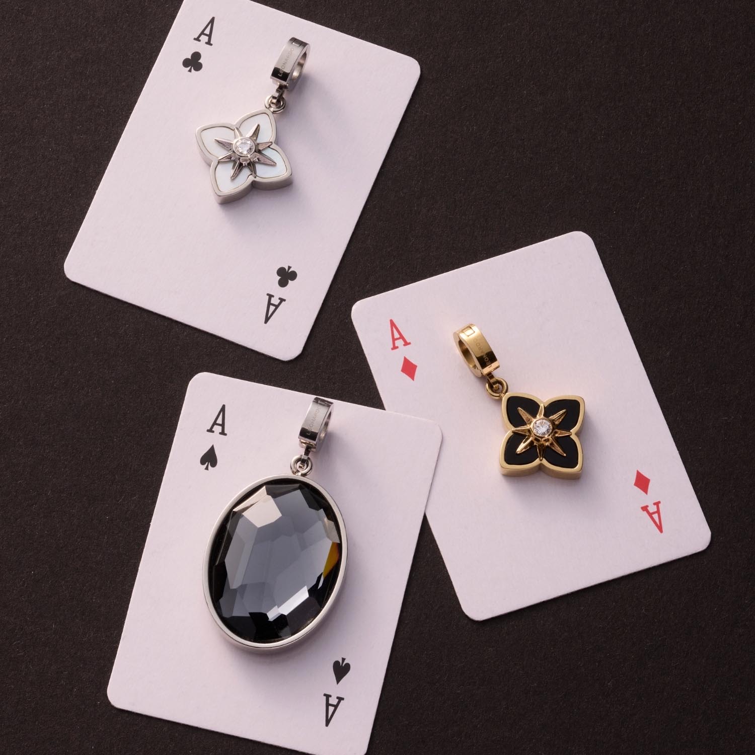 Drei Anhänger Clip & Mix auf Spielkarten arrangiert, mit verschiedenen Designs in Silber und Gold
