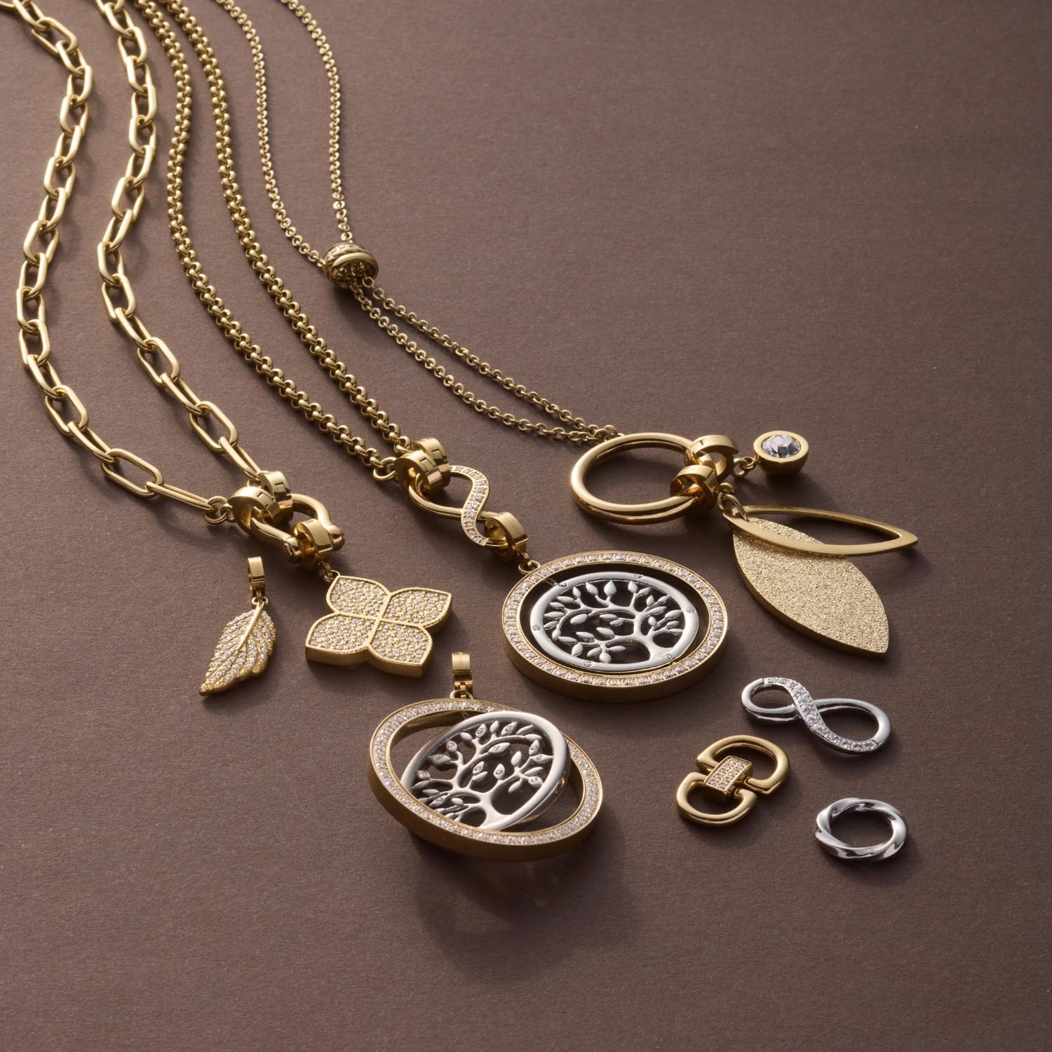 Anhänger FEDRA gold Clip & Mix mit Ketten und austauschbaren Charms auf braunem Untergrund