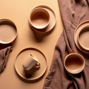 Keramikteller ROMA apricot, Tassen und Tischtuch in Flatlay-Anordnung