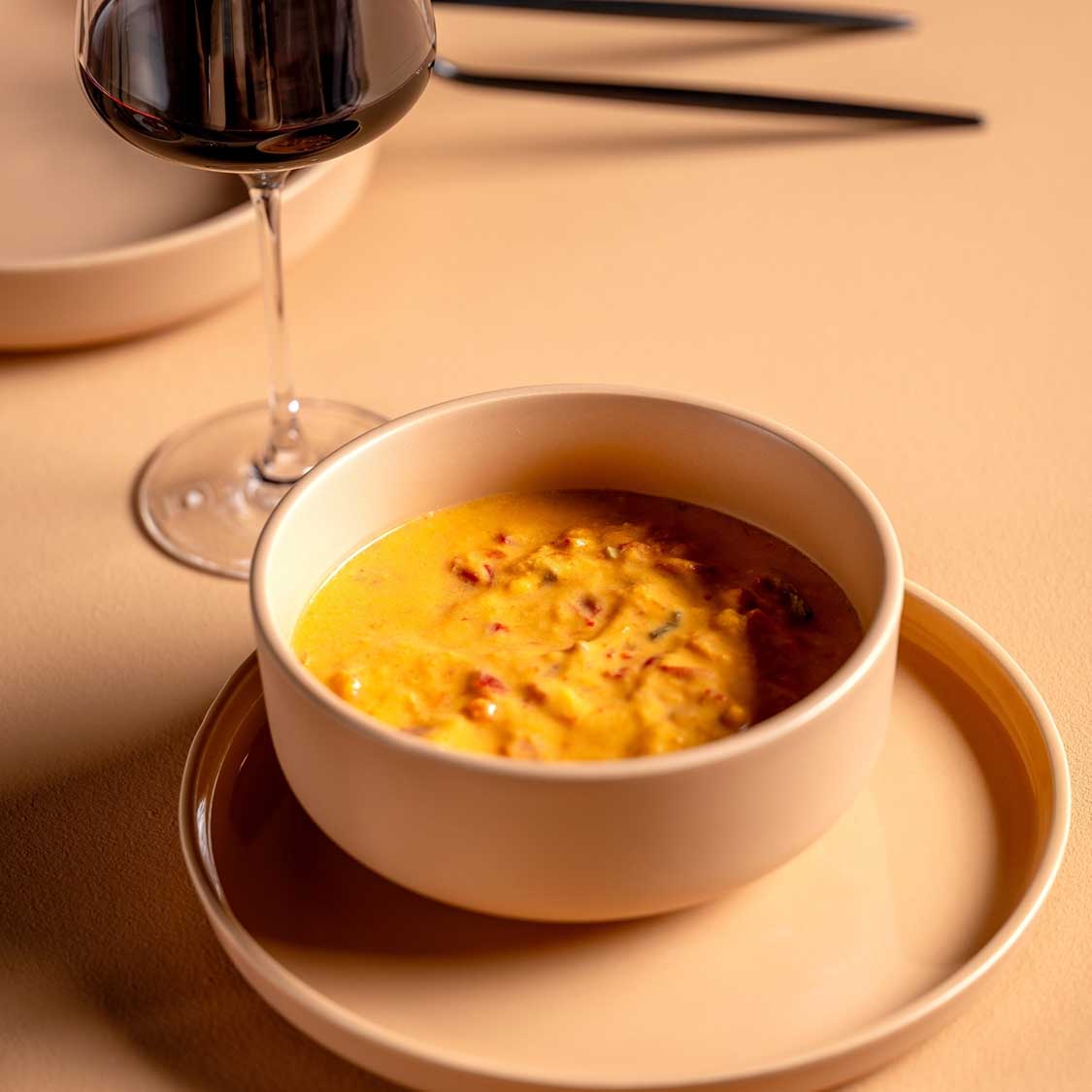 Keramikschale ROMA mit Suppe, Weinglas und Besteck auf apricot Tisch