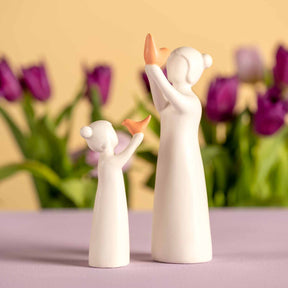 Weiße Keramikfigur Mädchen mit Vogel neben Tulpen in Dekorationsansicht